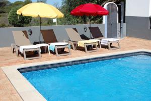 a swimming pool with lounge chairs and umbrellas next to a swimming pool at Charmante Villa mit 4 Schlafzimmer, Wlan und Zentralheizung in Santa Bárbara de Nexe +39 photos