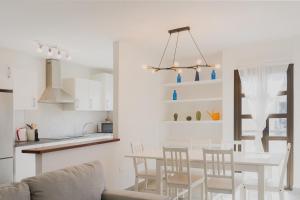een witte keuken en een eetkamer met een tafel en stoelen bij Happy House - Downtown Apartment in Corralejo