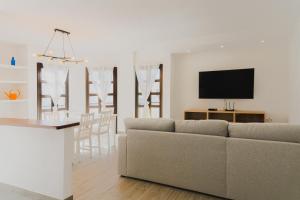een woonkamer en een keuken met een bank en een televisie bij Happy House - Downtown Apartment in Corralejo