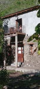 a small building with a balcony and a door at Hostal SPA Casa de Piedra in La Quebrada