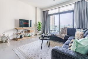 Una sala de estar con un sofá azul y una ventana grande. en GuestReady - Beach Vista in Marina Harbour, en Dubái