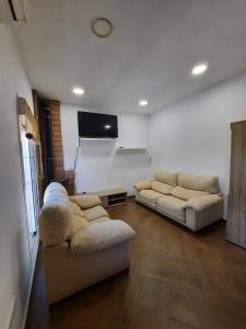 a living room with two couches and a flat screen tv at CASA RURAL A PIE DE PLAYA Remodelada 2024 in Chipiona