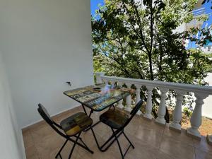 a table and chairs on a balcony with a tree at Angels Rooms in Ksamil