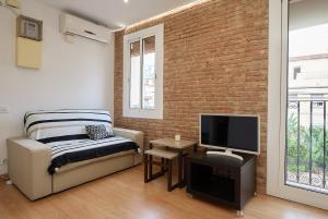 1 dormitorio con sofá, TV y pared de ladrillo en GuestReady - Acogedor Apt en La Barceloneta, en Barcelona