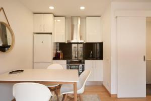 Una cocina con gabinetes blancos y una mesa y sillas. en GuestReady - Acogedor Apt en La Barceloneta, en Barcelona