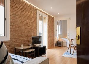 バルセロナにあるGuestReady - Acogedor Apt en La Barcelonetaのレンガの壁のリビングルーム(テレビ付)