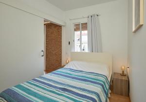 1 dormitorio con 1 cama con manta a rayas en GuestReady - Acogedor Apt en La Barceloneta, en Barcelona