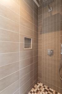 a bathroom with a shower with a tiled wall at Home by the Sea - Maison Cancale proche de la mer in Cancale