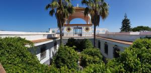 a building with palm trees in front of it at CASA RURAL A PIE DE PLAYA Remodelada 2024 in Chipiona