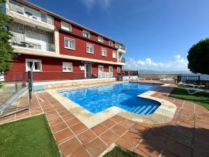 a swimming pool in front of a building at Apartamentos Sinás Playa in Raxó