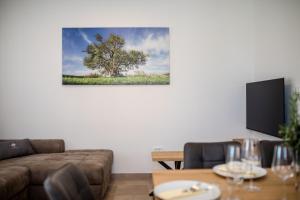 a living room with a couch and a tree on the wall at Apartma Stara Maslina in Rab