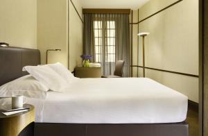 a bedroom with a large white bed and a chair at Hotel Balestri - WTB Hotels in Florence