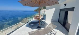 einen Balkon mit Stühlen, einem Sonnenschirm und dem Meer in der Unterkunft Sea Cliff Villa in Bar