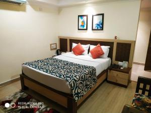 a bedroom with a large bed with orange pillows at Hotel Pushpak in Bhubaneshwar