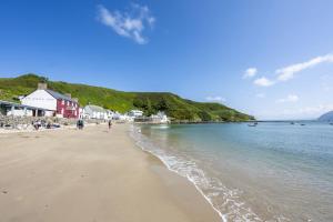a beach with people walking on the sand and the water at Y Granor in Pwllheli
