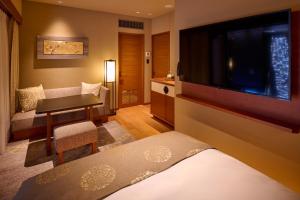 a hotel room with a bed and a flat screen tv at Sora Niwa Terrace Kyoto Bettei in Kyoto