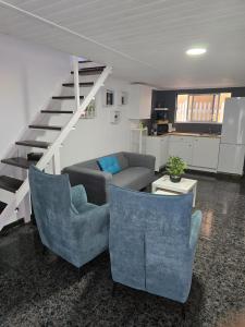Una sala de estar con un sofá y sillas y una escalera. en La Casablanca, en Pasito Blanco