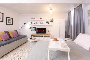 Biały salon z kanapą i telewizorem w obiekcie Joannas Sea-View Stone House w mieście Katávolos