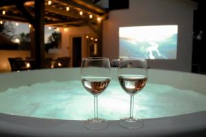 two glasses of white wine sitting on a table at Tóvidéki Kisház Nyírjes in Nyírjespuszta