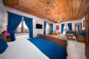 a bedroom with a large bed and blue curtains at Black Stove Cappadocia in Ortahisar