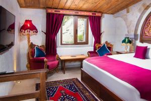 a bedroom with a bed and chairs and a window at Black Stove Cappadocia in Ortahisar