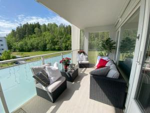 a porch with two chairs and a couch on a balcony at Spacious 3 Bedroom next to Thon Hotel, Storsenter Shopping, and 15 minutes to Oslo in Sandvika