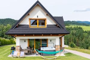 mały biały dom z czarnym dachem w obiekcie Czorsztyn Ski&Sail Aparthouse w mieście Maniowy
