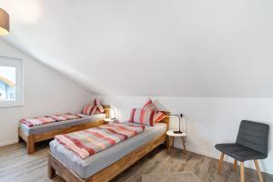 a bedroom with two beds and a chair at Neubau Ferienwohnung Kleine Auszeit in Sinzheim