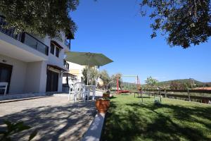 a patio with a table and an umbrella and a playground at Gem of Diaporos in Vourvourou