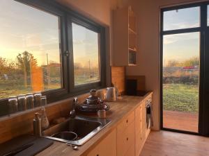 a kitchen with a sink and two large windows at Villa Les Terrasses in Ezerets