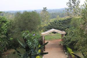 a bridge over a dirt road in a forest at Tinka,s Homestead in Fort Portal