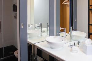 a bathroom with two sinks and two mirrors at Aloft by Marriott Aberdeen TECA in Aberdeen
