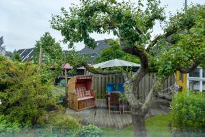 a backyard with a tree and a table and chairs at Ferienwohnung Alte Liebe in Cuxhaven