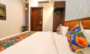a bedroom with a white bed with colorful pillows at Hotel California Heights in Amritsar