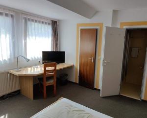 a room with a desk with a computer and a bed at Landgasthaus Römerhof in Obernburg am Main