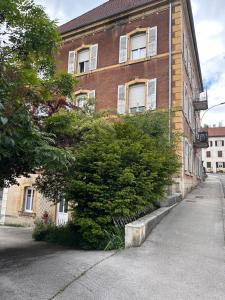 a brick building with a bush in front of it at Appartement T2 La Belle Epoque in Morteau