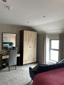a bedroom with a bed and a desk and a cabinet at Rooms at The Marine in Ballybunion