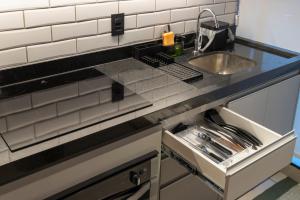 a kitchen counter with a sink and a drawer at Loft Marília City in Marília