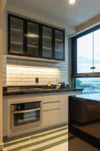 a kitchen with a stove and a sink and a window at Loft Marília City in Marília