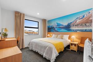 a hotel room with a bed and a painting on the wall at Sunshine Suites in Lake Tekapo