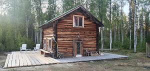 a log cabin with two chairs on a wooden deck at Gemütliche Blockhütte mit Außentoilette und Badezimmer im Haupthaus in Jörn