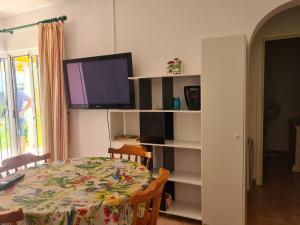 comedor con mesa y TV en un estante en As055 Noa - Cosy 2 bedroom in the green oasis, en San Juan de los Terreros