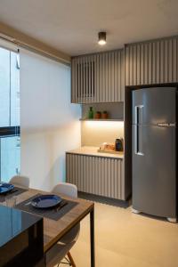 a kitchen with a stainless steel refrigerator and a table at Loft Marília City in Marília