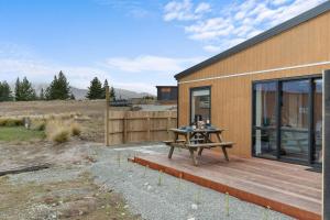 a wooden deck with a picnic table next to a building at Sunshine Suites in Lake Tekapo
