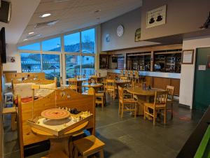 a restaurant with wooden tables and chairs and windows at Le Herbau in Gérardmer