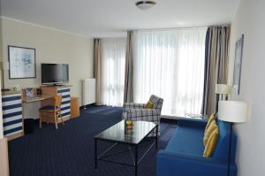 Habitación de hotel con sofá azul y mesa en Strandläufer App 205, en Zingst