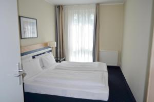 Una habitación de hotel con una cama blanca y una ventana. en Strandläufer App 205, en Zingst