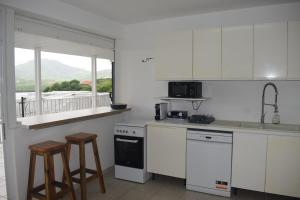 a kitchen with white cabinets and a sink and stools at CHAUDIERE DE RÊVE in Le Vauclin