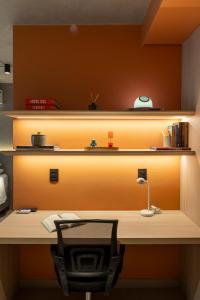 a desk with a chair in front of a shelf at Loft Marília City in Marília
