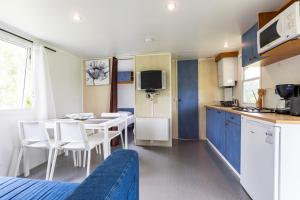 a kitchen and dining room with a table and chairs at L'héberge du lac d'Isachris mh6 in Queyrac